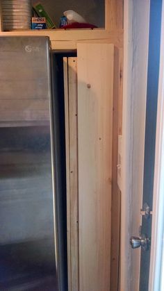 a stainless steel refrigerator and wooden shelves in a kitchen