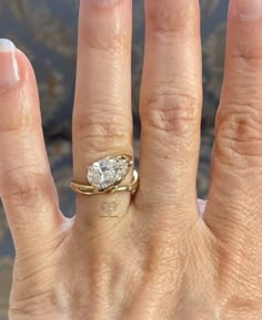 a woman's hand with a diamond ring on top of her finger and the other hand holding an engagement ring