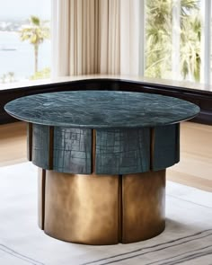 a round coffee table with two circular metal bases in front of a large window overlooking the ocean