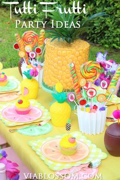 a table topped with lots of colorful desserts and candies next to a pineapple