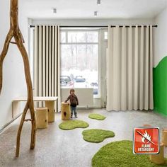 a child is sitting in the middle of a room with green rugs on the floor