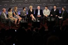 a group of people sitting on stage in front of a crowd at a panel event