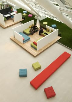 two people sitting at a table in a room with green grass on the floor and white walls