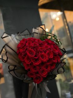 a bouquet of red roses sitting on top of a table next to a store window