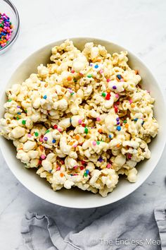 a white bowl filled with popcorn and sprinkles on top of a table