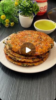 a stack of pancakes sitting on top of a white plate next to bowls of sauce