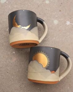 two coffee mugs with designs on them sitting on the ground next to each other