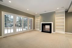 empty living room with fireplace and built - in bookcases on either side of sliding glass doors