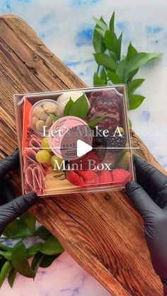 a person in black gloves holding up a clear box filled with different types of food