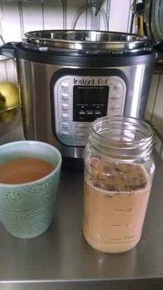 a jar of liquid next to an instant pot and cup of tea on a counter