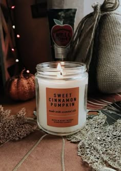 a white candle sitting on top of a table next to a bag and pumpkins