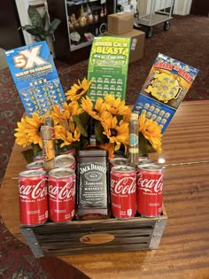 an arrangement of sodas and sunflowers in a crate on a coffee table