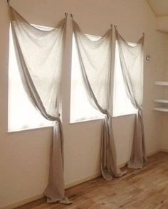 three windows with sheer curtains in an empty room