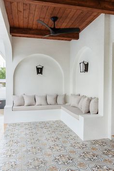 a room with white walls and tile flooring has a ceiling fan in the corner