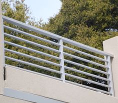 a skateboarder is doing a trick on a rail over a bridge in front of some trees