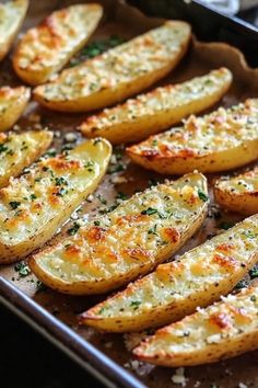 baked potato wedges with parmesan cheese and herbs on a baking sheet, ready to be eaten