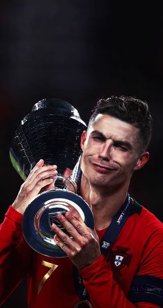 a man holding up a trophy in his right hand and wearing a red shirt on the other side