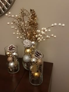 two vases filled with ornaments sitting on top of a wooden table next to a mirror