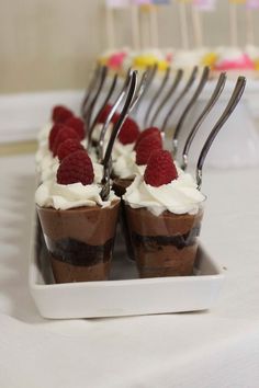 chocolate desserts with raspberries and whipped cream are arranged on a white plate