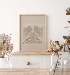 a table with some vases and plants on it next to a framed art piece