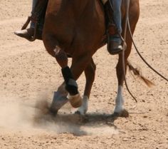 a man riding on the back of a brown horse in an open field with dirt