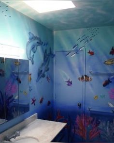 a bathroom decorated in blue and white with dolphins on the wall, fish under water