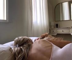 a woman laying on top of a bed next to a dresser with a mirror above her head