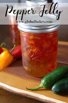 two jars filled with peppers sitting on top of a wooden cutting board