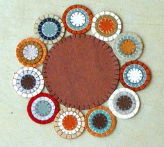 a circular design made out of various colored glass and ceramic tiles on a white surface