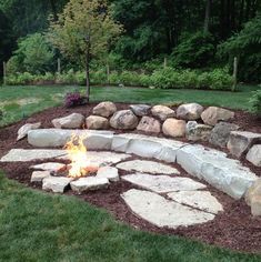 a fire pit surrounded by rocks and grass