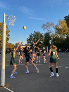 girls playing basketball on an outdoor court with the ball in the air above their heads