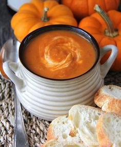 a bowl of soup with bread and pumpkins in the background