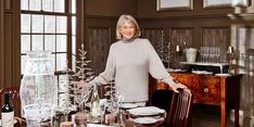 a woman standing in front of a table with plates and glasses on top of it