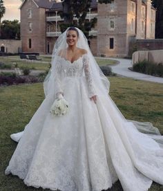 a woman in a wedding dress standing on the grass with her arms around her waist