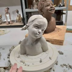 a person is working on a clay busturine in front of some other figurines