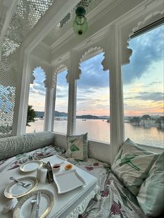 the sun is setting over the water in this room with large windows that look out onto the ocean