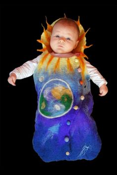 a baby wearing a sunflower costume with the earth in it's center, on a black background