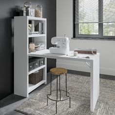 a sewing machine sitting on top of a white table next to a window with blinds