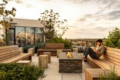 a man sitting on top of a wooden bench next to a fire pit in a park