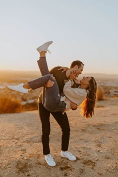 a man and woman are dancing in the desert with their feet up on each other