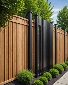 a wooden fence surrounded by shrubbery and bushes in front of a sidewalk with trees on both sides