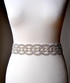 a white mannequin with a silver belt on it's waist and some beads