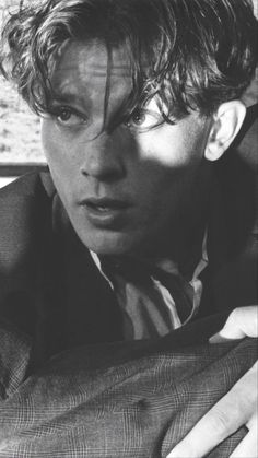 black and white photograph of a young man with curly hair looking at the camera while sitting in a car