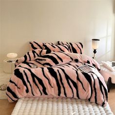 a bed covered in pink and black zebra print comforter next to a night stand