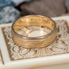 two gold wedding bands sitting on top of a white tile