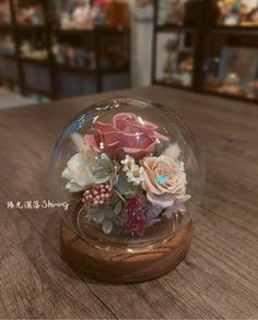 there is a glass ball with flowers in it on top of a wooden table next to other items