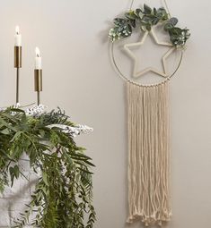 a star hanging on the wall next to a candle and some greenery in front of it