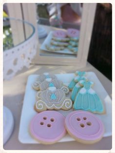 some decorated cookies are sitting on a plate next to a mirror and cupcakes