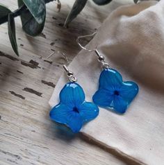 a pair of blue flower earrings sitting on top of a wooden table