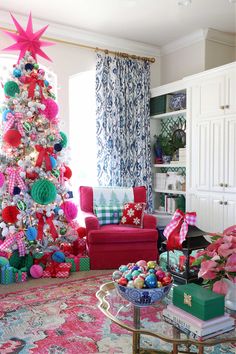 a decorated christmas tree in the corner of a living room with pink and green decorations